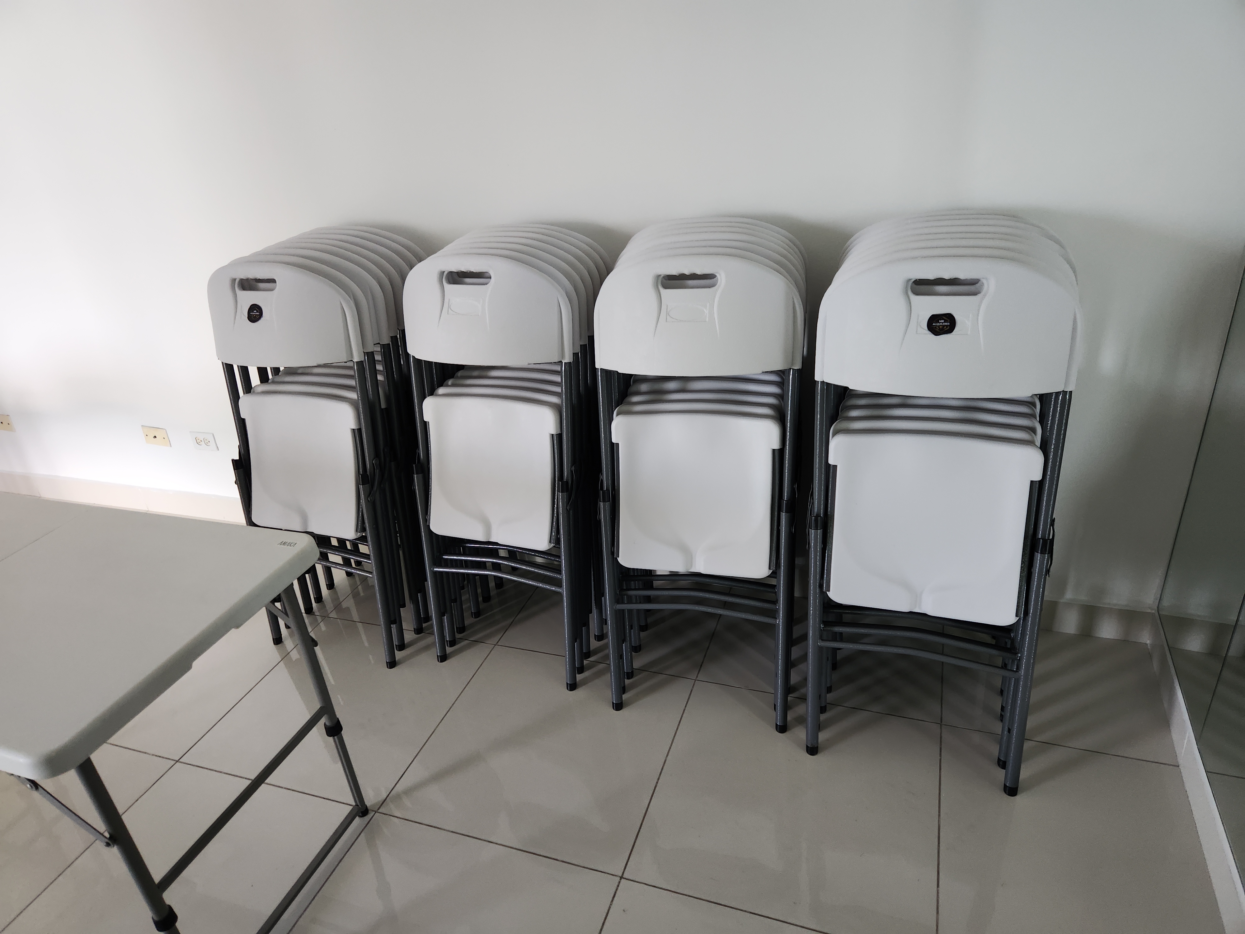 Sillas plegables apiladas en almacén, listas para alquiler